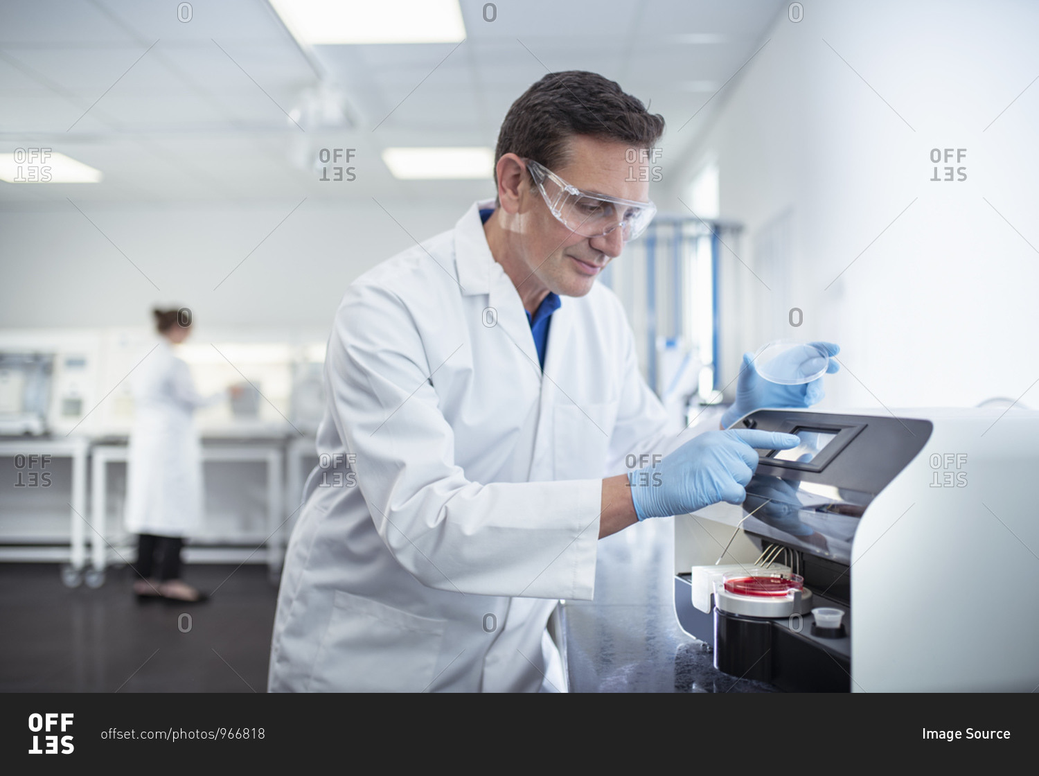 Scientist operating agar dish coating machine in laboratory