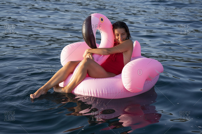 Woman on flamingo float on sea, Italy