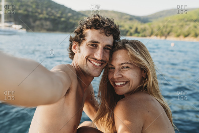 Couple taking selfie by seaside, Italy