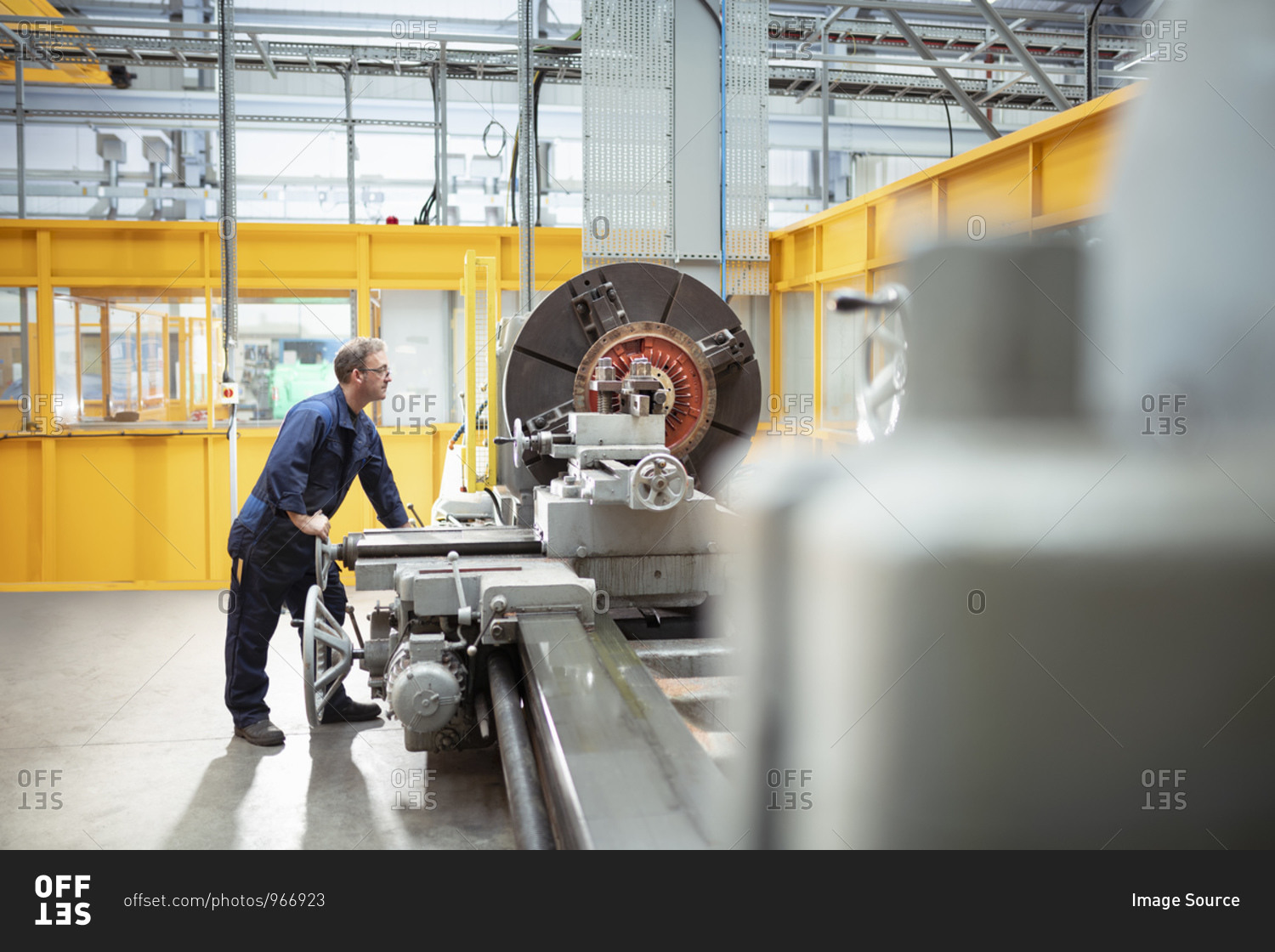 Wide angle view of engineer operating lathe in electrical\
engineering factory stock photo - OFFSET