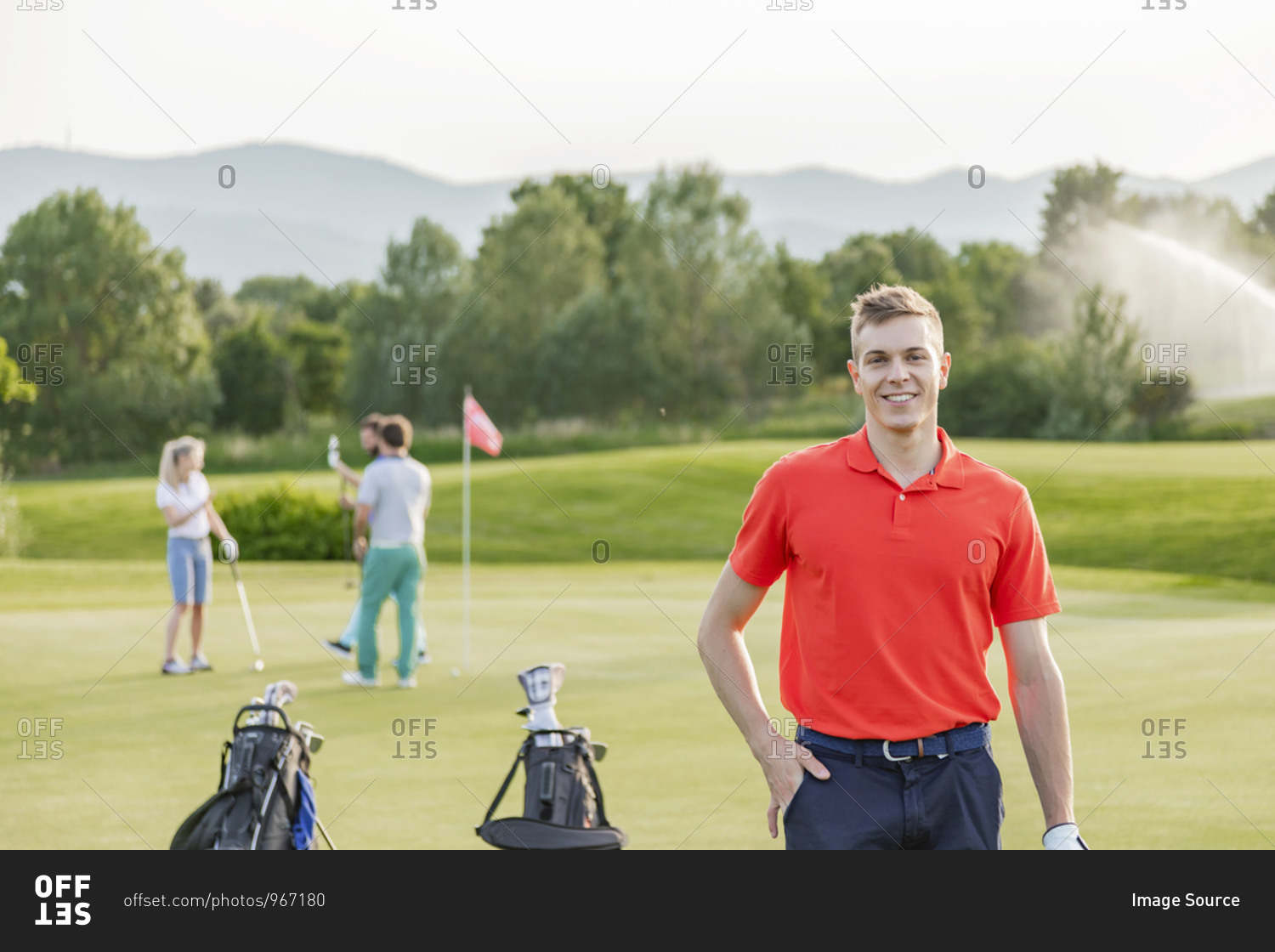 Man with friends playing golf on golf course in background