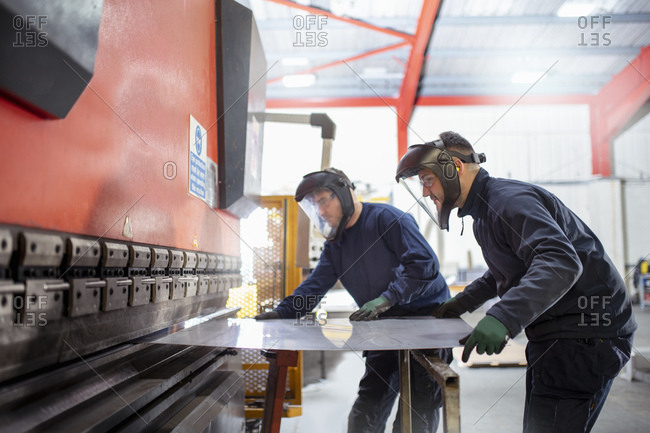 Worker bending sheet metal in metal fabrication factory.