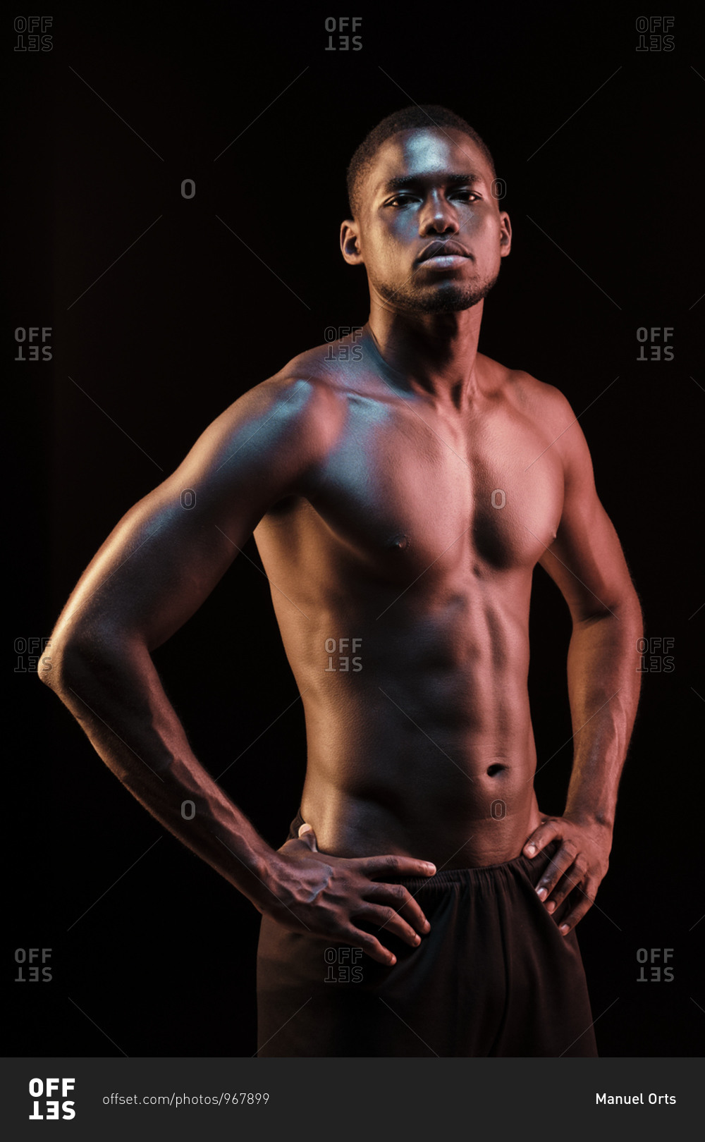 Standing black man looking at camera with his hands on his hips lit ...