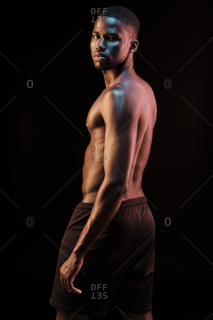 Black man looking at camera lit with colored lights