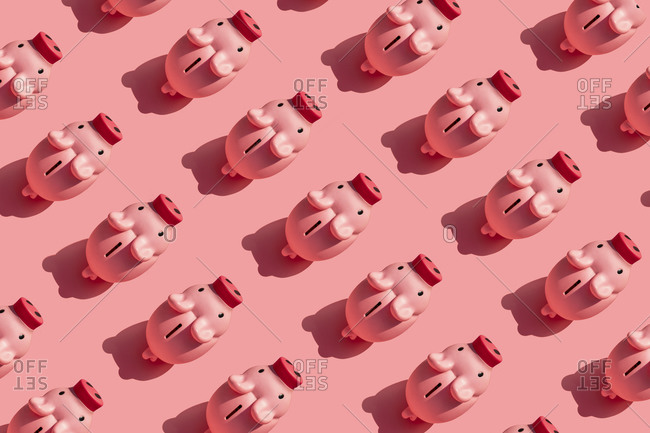 Seamless pattern of rows of piggy banks against pastel pink background