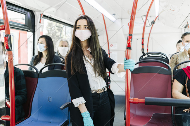 Portrait of young woman wearing protective mask and gloves in public bus- Spain