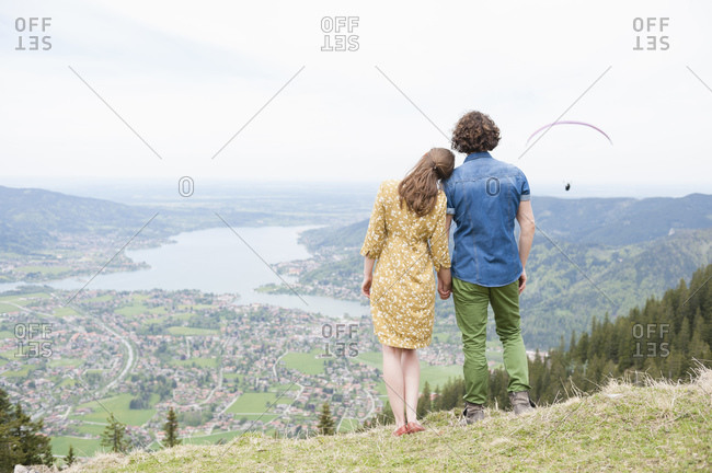 Mid adult couple holding hands while looking at landscape from mountain peak