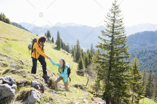 Man helping his woman climbing rock- Wallberg- Bavaria- Germany