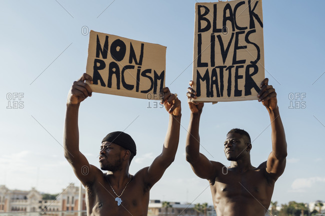 Two men holding Black Lives Matter and anti racism signs in the street