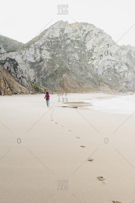 Mid distance of woman leaving footprints while running at Ursa Beach- Lisboa Region- Portugal