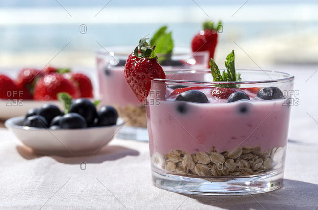 Homemade yogurt with strawberries, blueberries and cereals with pink tablecloth and sunlight, Healthy food concept, Vegan food
