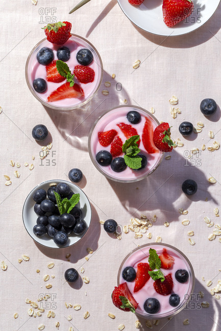 Homemade yogurt with strawberries, blueberries and cereals with pink tablecloth and sunlight from above, Healthy food concept, Vegan food