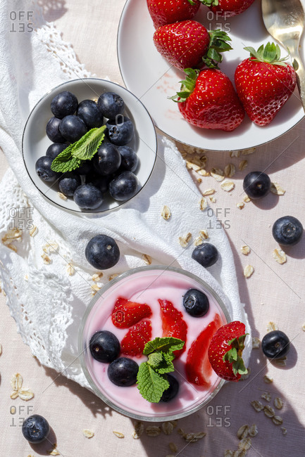 Homemade yogurt with strawberries, blueberries and cereals from above with pink tablecloth and sunlight, Healthy food concept, Vegan food