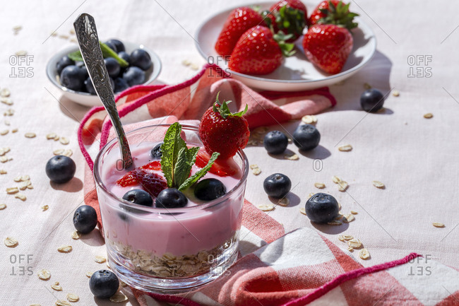 Homemade yogurt with strawberries, blueberries and cereals with pink tablecloth and sunlight, Healthy food concept, Vegan food
