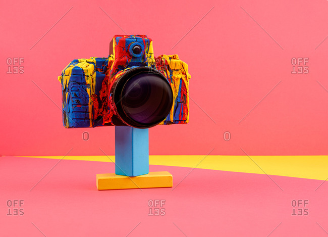 Creative retro photo camera painted with various colors arranged on colorful background