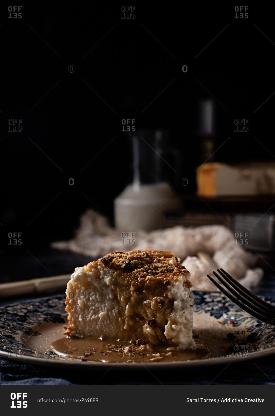 Cheese cake with delicious liquid caramel in composition with ingredients and utensil among delicate fabrics on blue marble table