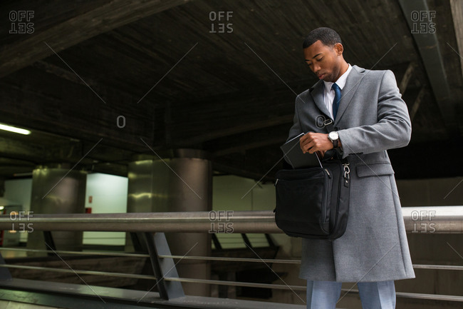 Handsome African-American man in suit checking bag