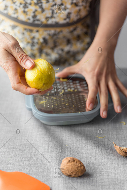 Woman scratching a lemon with a grater