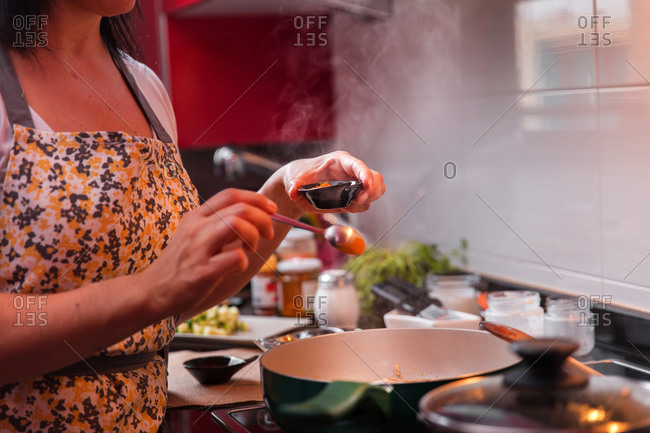 Woman cooking with oil on the stove