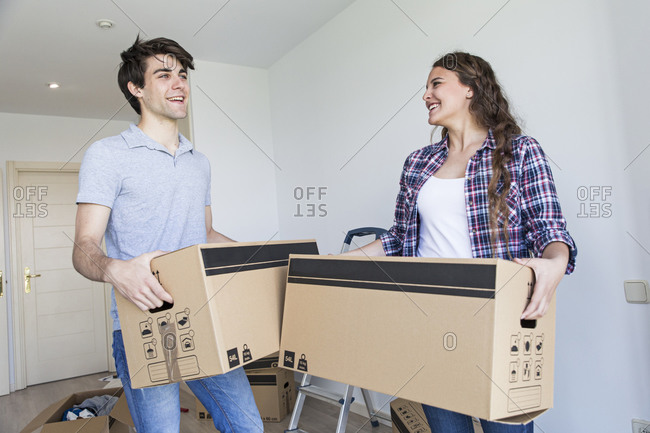 Young couple holding carton boxes in new apartment taking and smiling