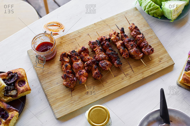 Cooked chicken skewers with spicy sticky glaze on wooden cutting board