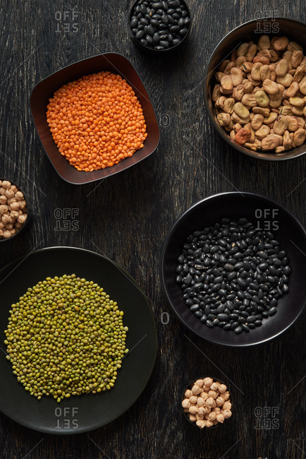 Healthy organic vegetarian food - natural organic beans - red and green lentils, chickpea and black kidney beans on a dark wooden background, copy space. Top view. Vegan food concept.