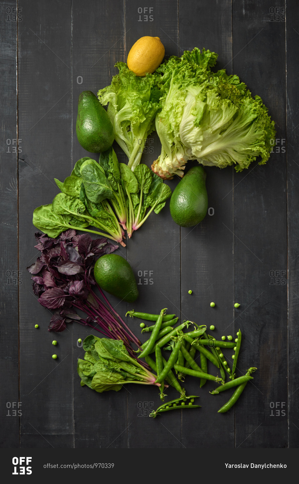 Vegetable frame from home grown fresh natural organic greenery, pear pods, avocado and lemon fruits on a dark wooden background, copy space. Top view. Vegetarian healthy food.