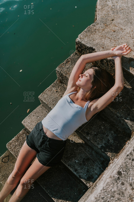 Young woman sunbathing on steps by Lake Jablanica in Bosnia and Herzegovina