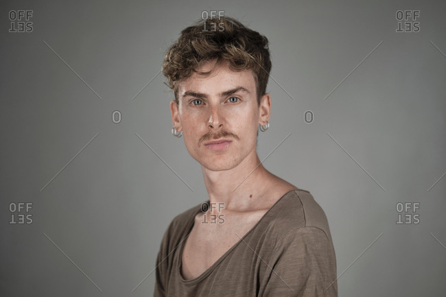 Selective focus portrait of a young blonde man with blue eyes and mustache