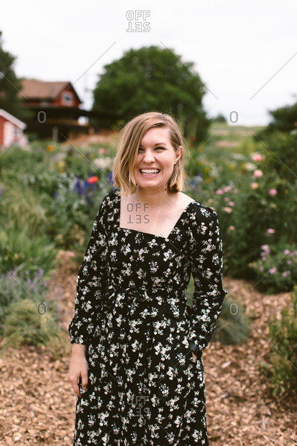 Smiling blonde woman in a floral dress in her flower garden