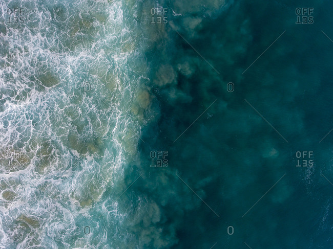 Foamy turquoise waves in the ocean, aerial view
