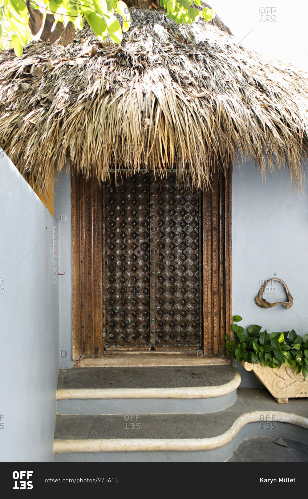 Wooden entrance on blue house with a thatch roof