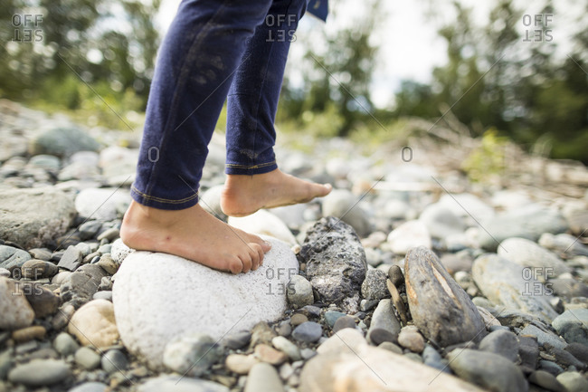 Girl standing barefoot on pebbles