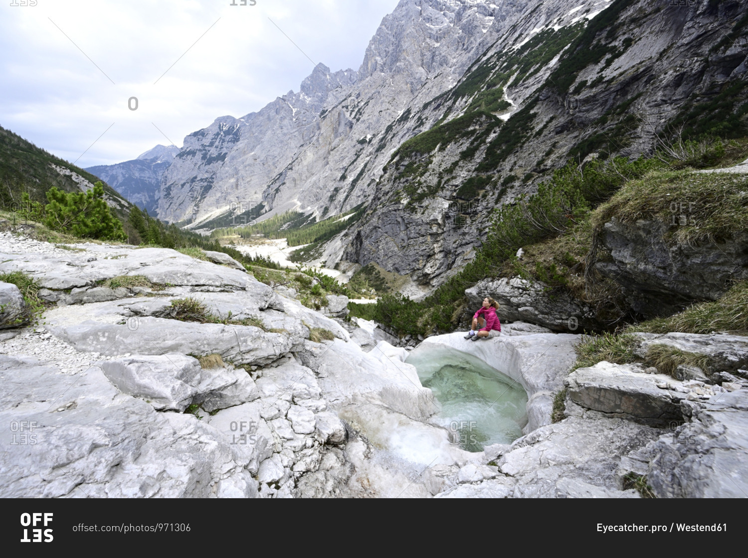 Mature woman exploring mountains while sitting by stream