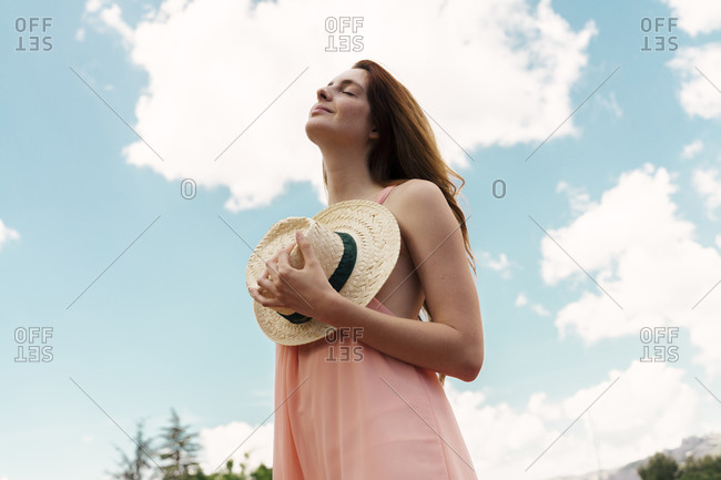 Portrait of redheaded woman with straw hat and closed eyes