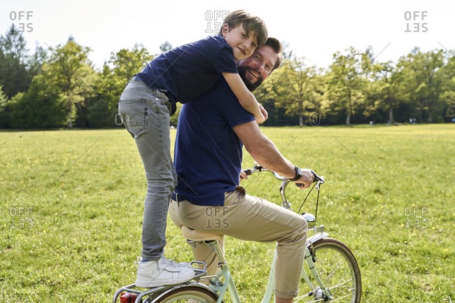 Happy boy embracing father while enjoying bicycle ride on sunny day