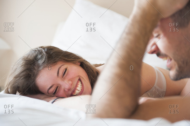 Woman unhooking bra on bed stock photo - OFFSET