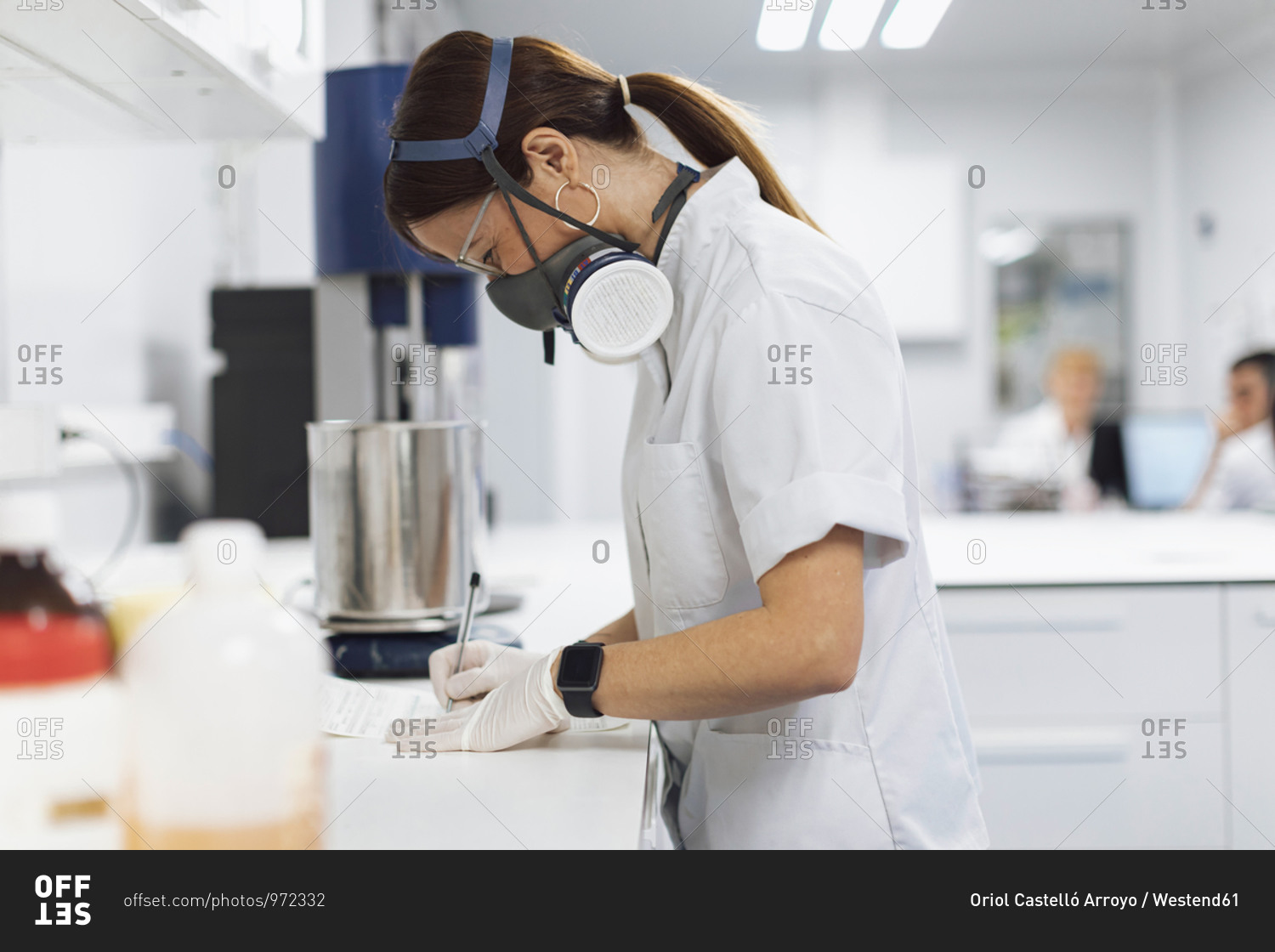 Mature female pharmaceutical technician writing data at desk in laboratory