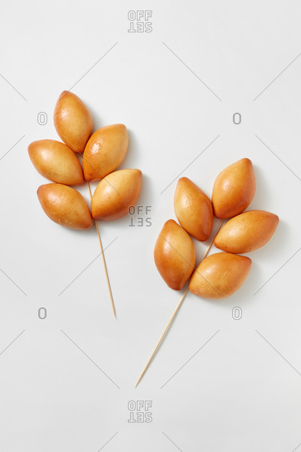 Creative composition from freshly baked homemade buns in the form of wheat ears on a white background, copy space. Top view.