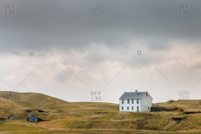 White Icelandic farm house with grass roof shed on a cloudy day in Southern Iceland