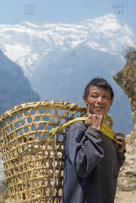 A Nepali man in the Everest region carrying a Doko which is a traditional style of basket made of bamboo and carried on the head with a Namlo or head strap
