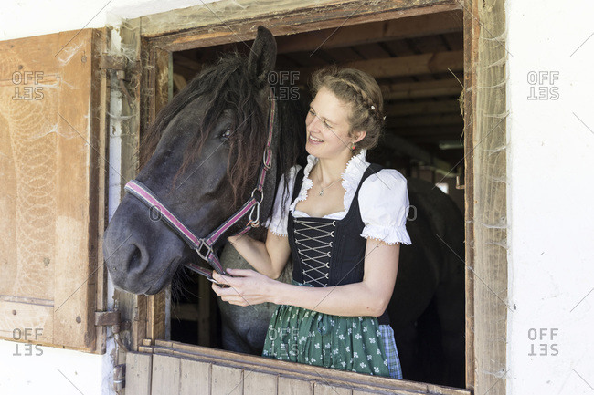 Farmer with dirndl strokes a horse