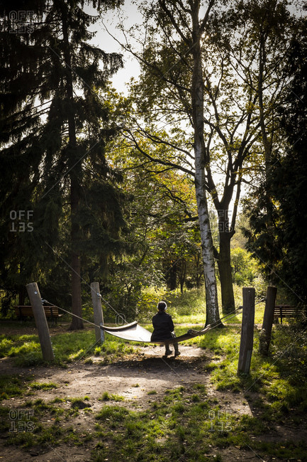 Woman is sitting on a hammock in the park