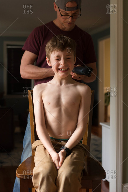 Boy nervously gets ready to get a haircut from his dad