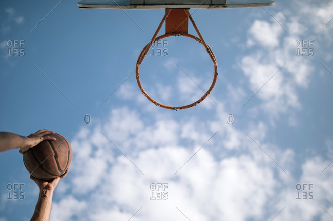 Teen boy putting basket into hoop on a basketball court