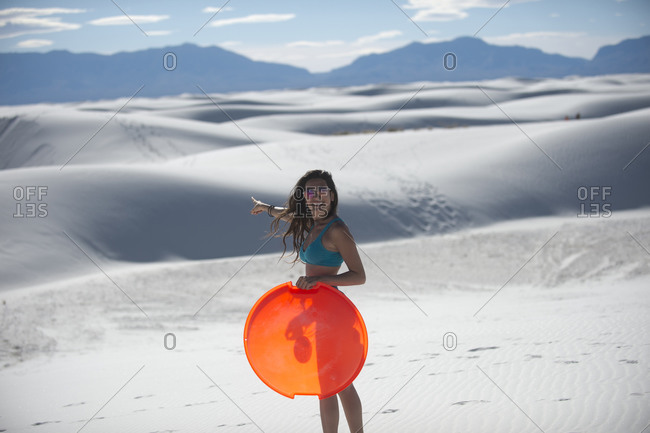 Woman holding sled in desert, White Sands National Monument, New Mexico, USA
