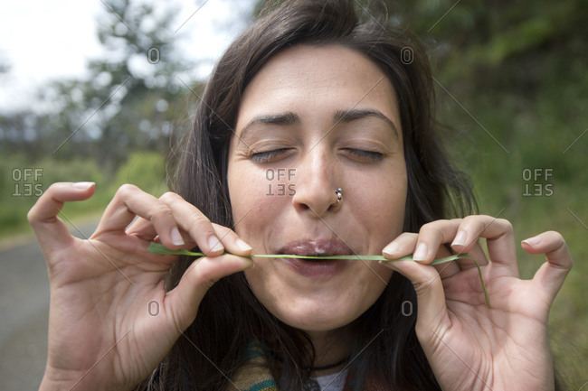 Woman trying to whistle with blade of grass, New Mexico, USA