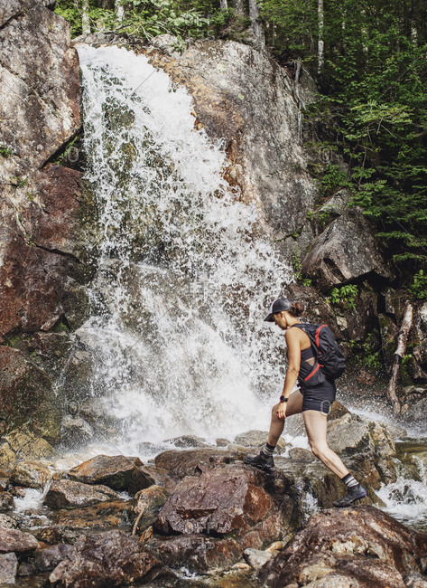 Female hiker walking near waterfall, White Mountains, New Hampshire, USA