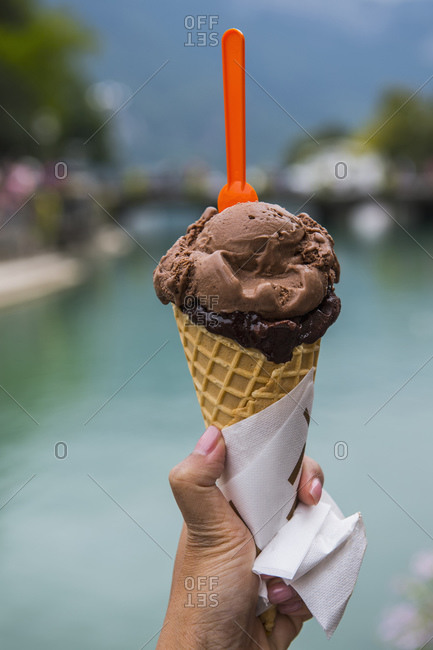 Hand of woman holding ice cream cone with chocolate ice cream, Annecy, Auvergne-Rhone-Alpes, France