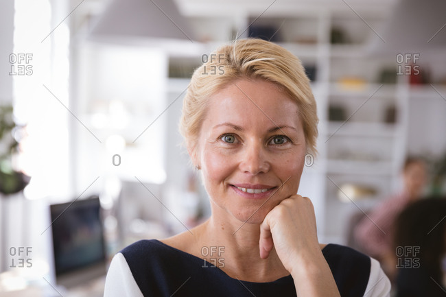 Portrait of a happy Caucasian businesswoman working in a modern office, looking at camera and smiling, with her colleagues working in the background
